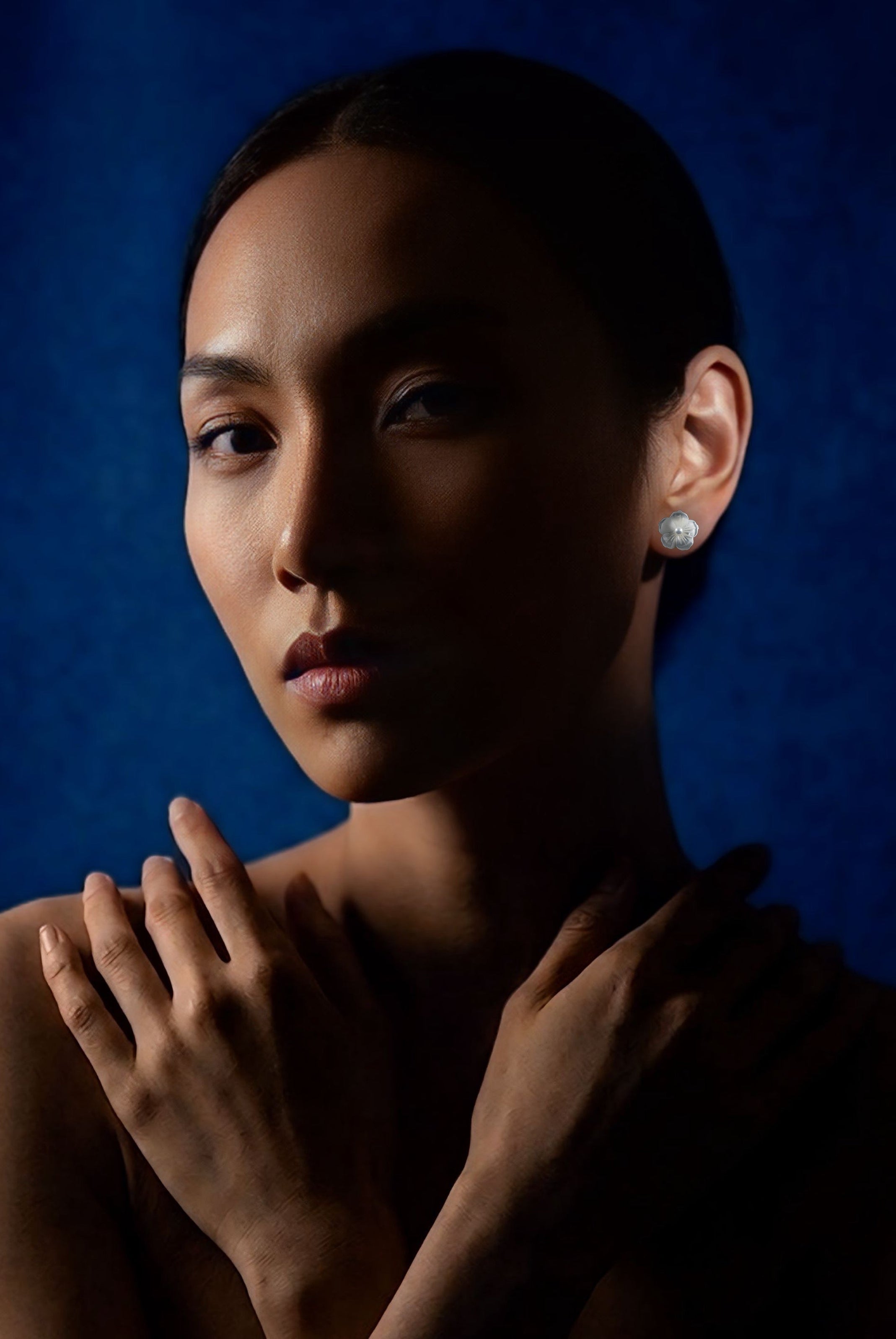 Woman with hands on shoulders against a dark blue background